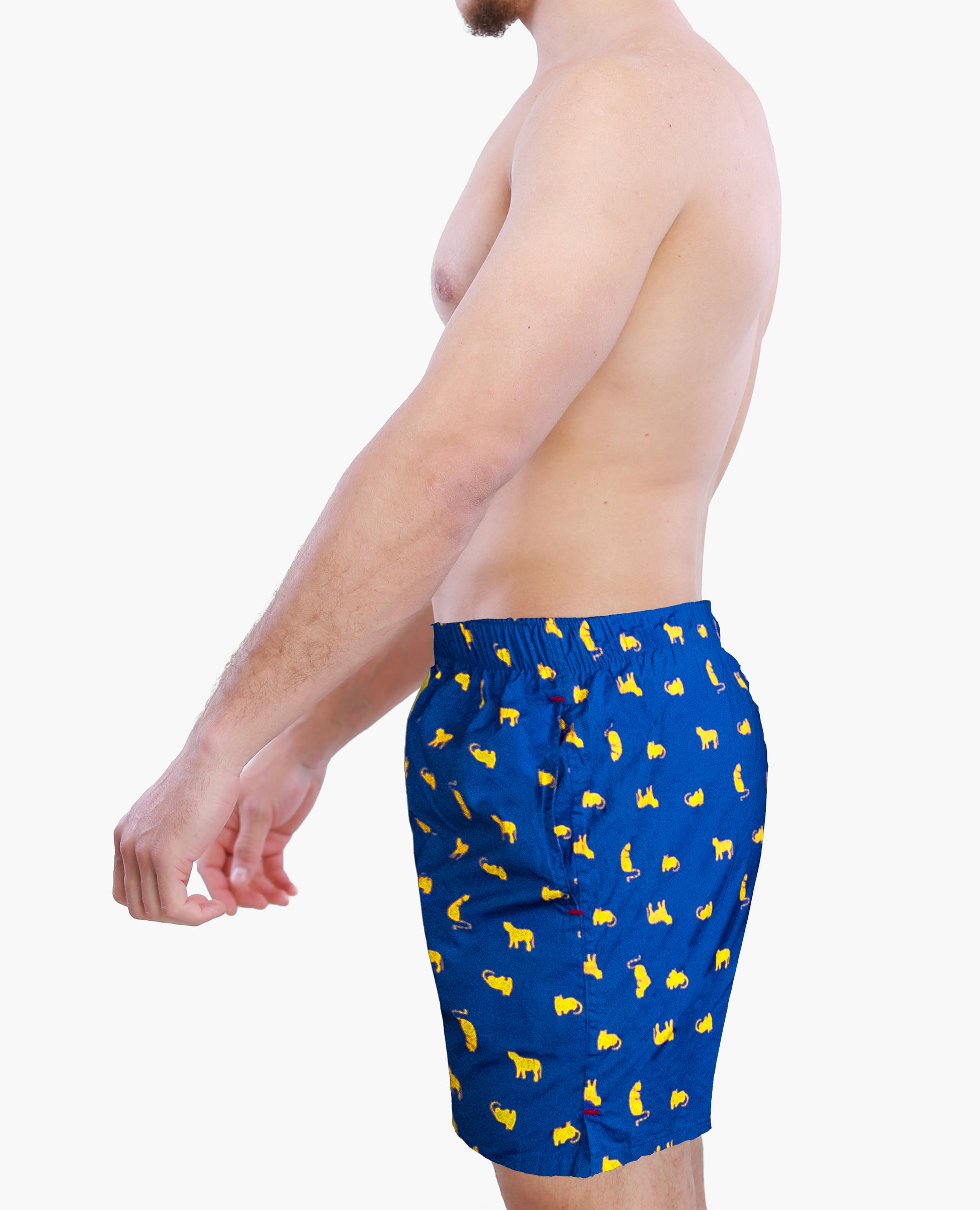 Side view of a male model wearing blue boxer shorts with yellow cats graphics on a white background