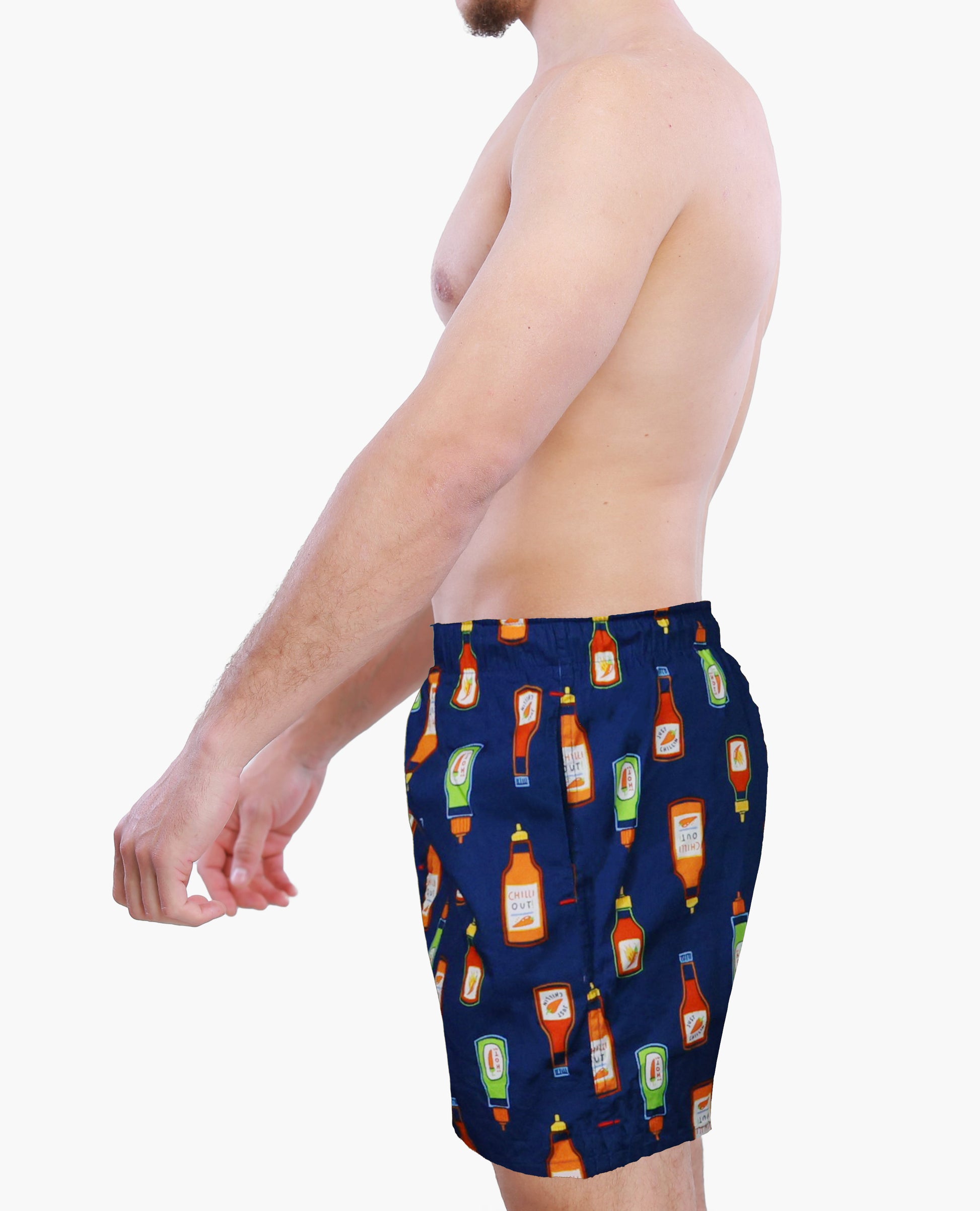 A side view of a male model wearing Weunderlust Navy blue boxer shorts  with hot sauce bottle pattern on a white background