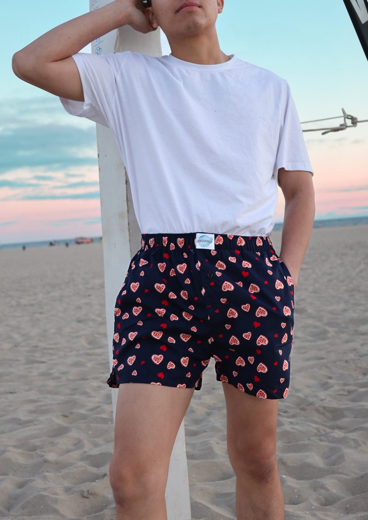 Front side of Male Model in Weunderlust Woven Cotton Boxers with pockets at the beach, Sweethearts, Navy, Hearts printing