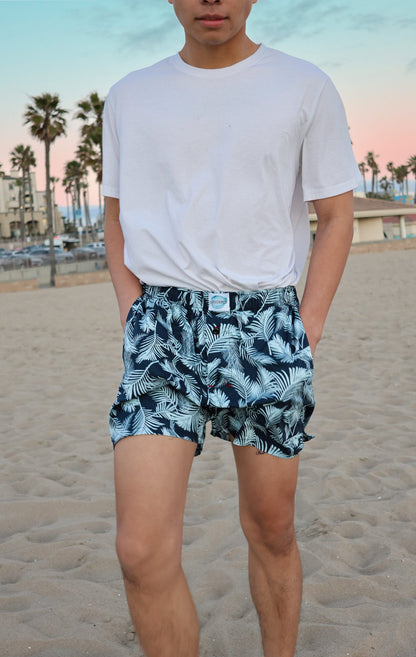 Front side of Male Model in Weunderlust Woven Cotton Boxers with pockets at the beach, Tropical, leaf printing, Blue, Navy