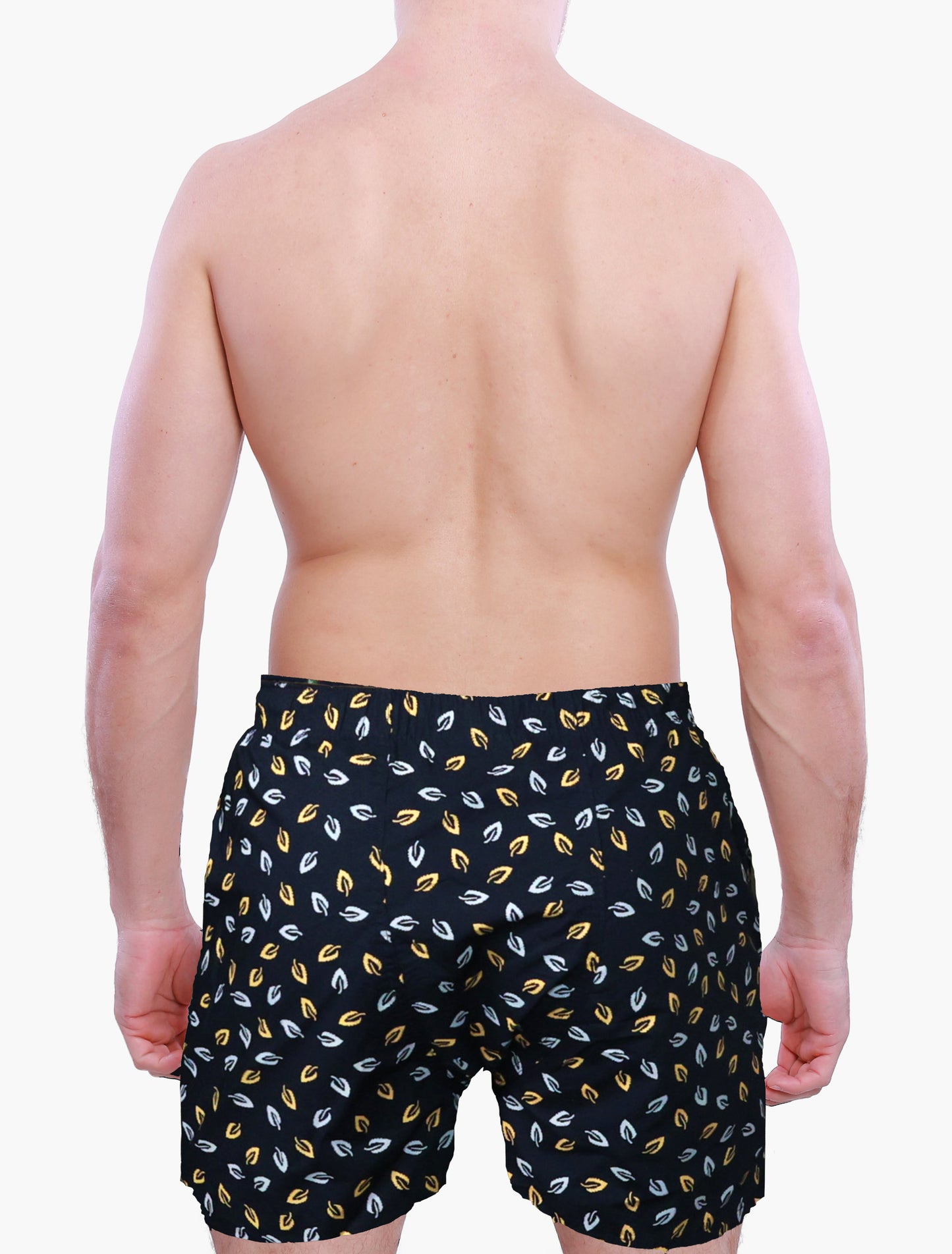 Back side of male model wearing black swim trunks with yellow and white leaf pattern on a plain background