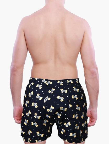 Person wearing black boxer shorts with yellow dog pattern on a white background