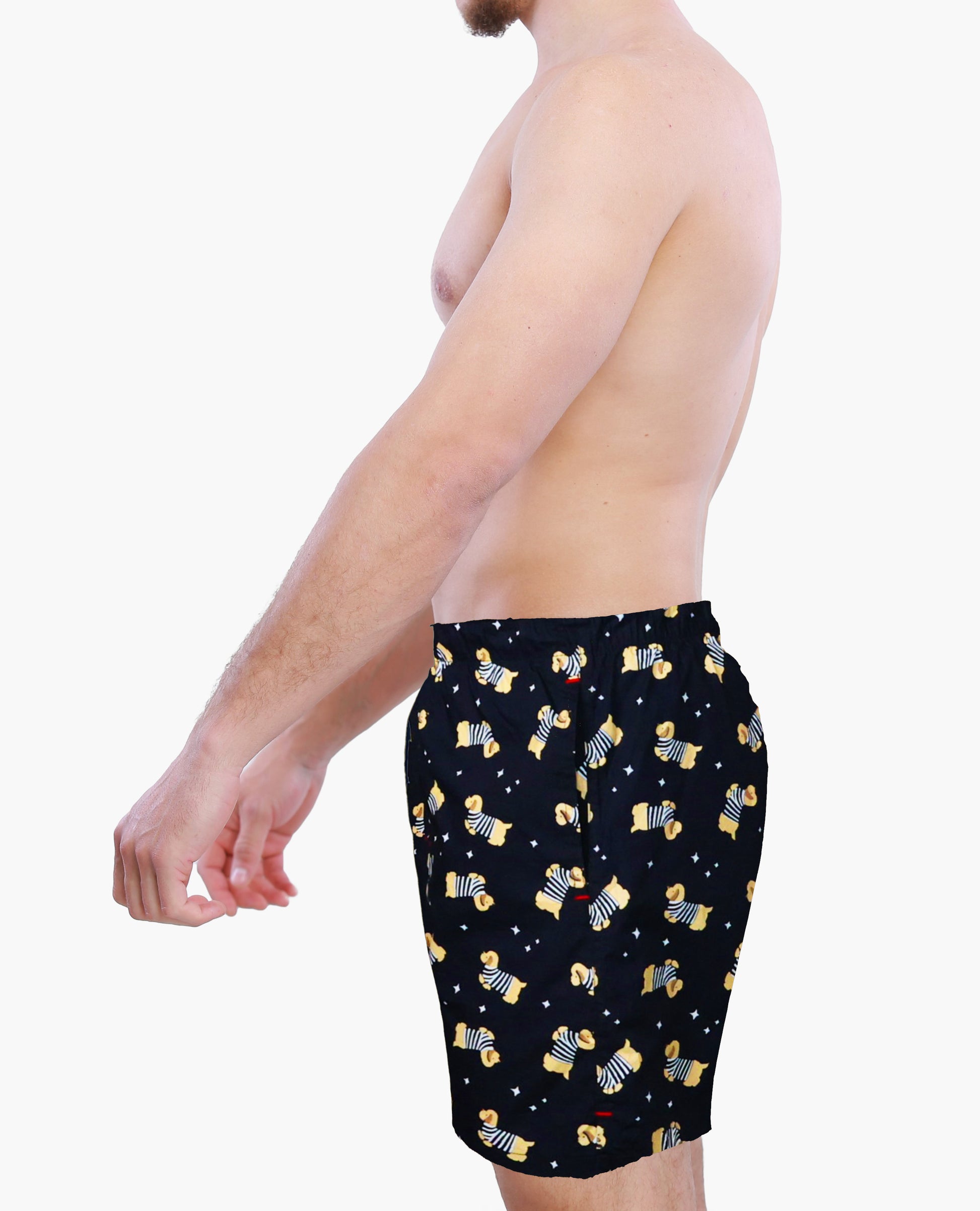 Man wearing black swim shorts with yellow dogs pattern on a white background