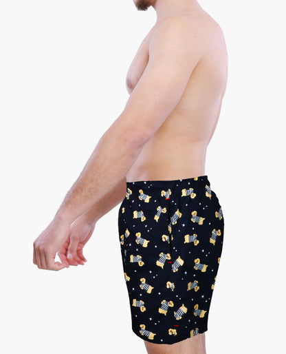 Man wearing black swim shorts with yellow dogs pattern on a white background