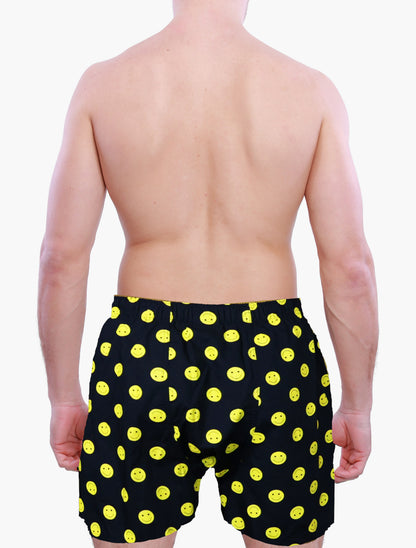 Person wearing black boxer shorts with yellow smiley face pattern on a white background