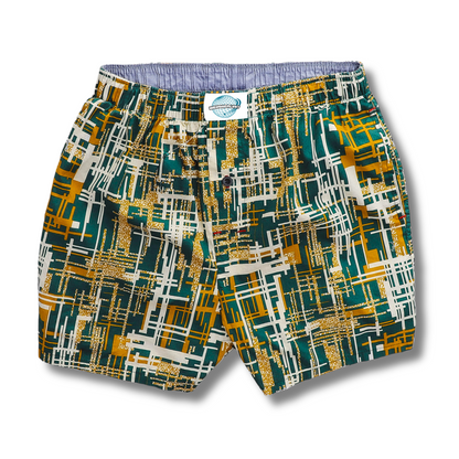 A pair of men's woven cotton boxer shorts with a geometric pattern featuring green, yellow, and blue colors, and a brand tag visible on the waistband.